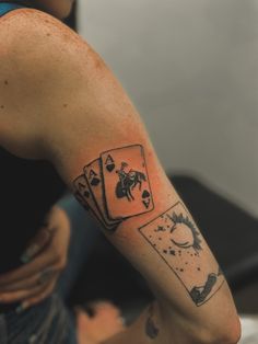 a woman with a tattoo on her arm holding four playing cards in front of her