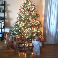 a small child standing in front of a christmas tree