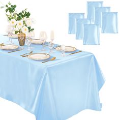 a blue table cloth with white flowers and place settings on it, along with napkins