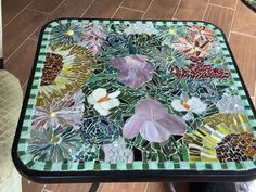 a glass table with flowers on it in the middle of tiled flooring and wood floors