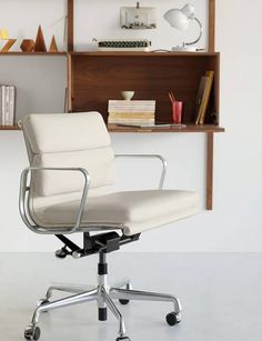 a white office chair sitting in front of a book shelf