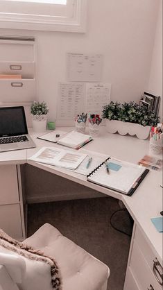 an office desk with a laptop computer on it and lots of papers in front of it