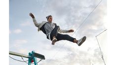 a man flying through the air while riding a skateboard next to a blue pole