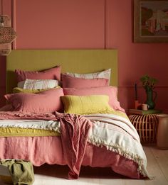 a bedroom with pink walls and yellow bedding