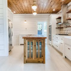 a large kitchen with white cabinets and wood ceilinging on the walls, along with an island in the middle