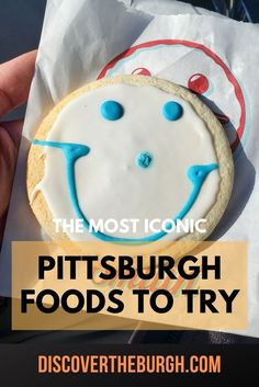 a close up of a person holding a cookie with the words, the most iconic pittsburgh foods to try