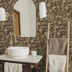 a white sink sitting under a bathroom mirror next to a wooden table with towels on it