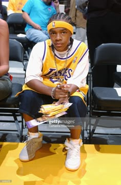 a young man sitting in the stands at a basketball game wearing a headband and sneakers