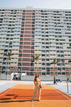 a woman standing on top of a tennis court in front of a tall apartment building