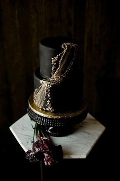 a black and gold wedding cake with flowers