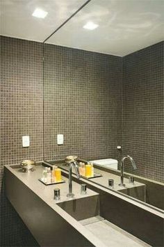 a bathroom with two sinks, mirrors and soap dispensers on the wall