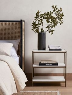 a bedroom with a bed, nightstand and plant