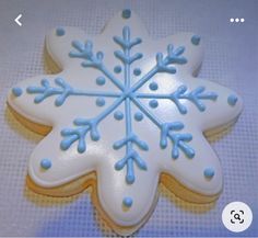 a cookie decorated with blue and white icing on a tableclothed surface,