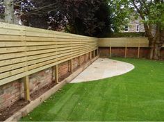 a wooden fence next to a lush green yard