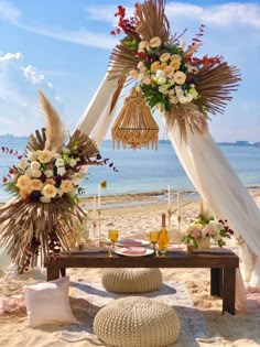 a table set up on the beach with flowers and candles