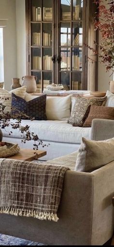 a living room filled with furniture and bookshelves next to a window covered in fall leaves