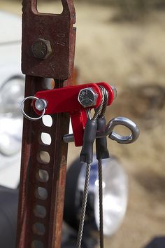 a close up of a pair of scissors attached to a piece of wood with hooks