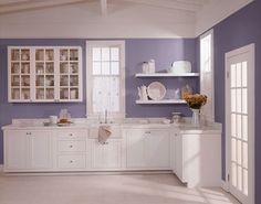 a kitchen with purple walls and white cabinets in the center, along with lots of open shelving