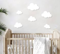 a baby crib with white clouds on the wall and palm trees in the background