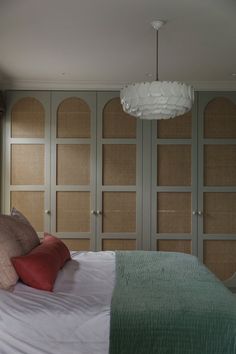 a bed with white sheets and pillows in a bedroom next to a closet full of cabinets