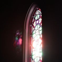 a stained glass window in the dark with light coming from it's center piece