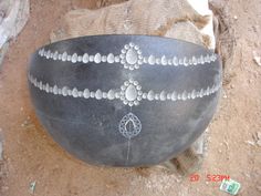 a large black bowl sitting on top of a dirt ground