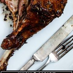 a piece of meat sitting on top of a white plate next to a knife and fork