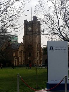 there is a sign in front of a large building with a clock tower on it