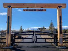 a gated entrance to a ranch with mountains in the backgroud and blue sky