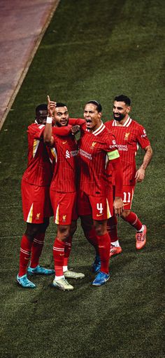 three men in red uniforms standing on a soccer field