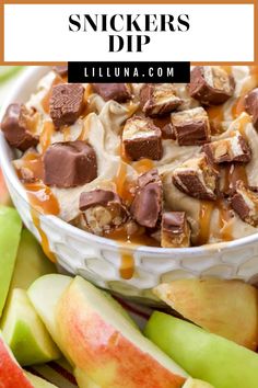 an apple dessert with caramel sauce and snickkers dip in the bowl next to sliced apples