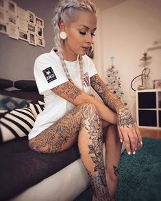 a woman sitting on top of a bed covered in tattoos