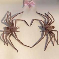 two large spider sculptures sitting next to each other on a white surface with a pink bow