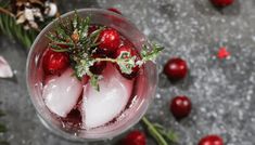 a glass filled with ice and cherries on top of a table covered in snow