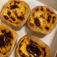 four pastries in a box with cheese on top