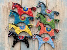 four colorful horses are hanging on a wooden wall, each painted different colors and patterns