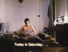 a woman sitting on top of a bed next to a pile of books in a room