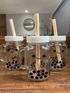 three mason jars with wooden straws in the lids and polka dots on them, one has a face drawn on it