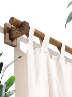 a curtain is hanging on a wooden rod next to a potted plant in front of a white wall