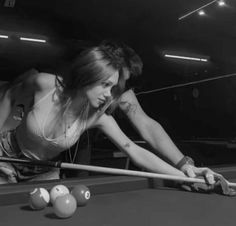 a woman is playing pool in a black and white photo