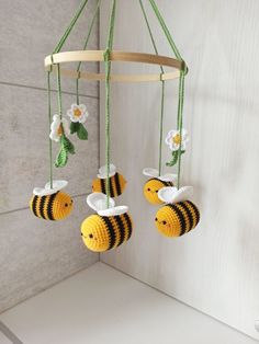 a crocheted mobile with three bees hanging from it's sides and flowers in the middle