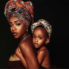 two women with headscarves on their heads are posing for the camera, one is holding her child