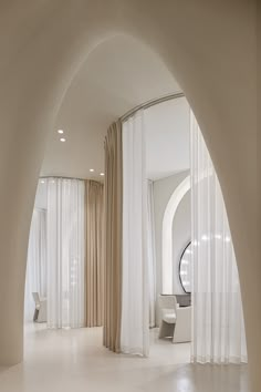 an arched hallway with white drapes and curtains