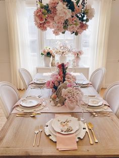 a dining room table set with flowers and place settings