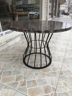 a table that is sitting on the ground in front of a storefront with cars parked behind it