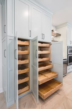 an open cabinet in the middle of a kitchen with wooden shelves and drawers on both sides