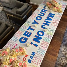 a large sign that says get your popcorn now on the floor next to couches