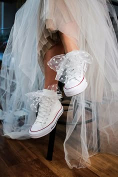 a woman in white shoes is sitting on a chair with a veil over her legs