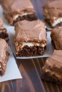 several pieces of cake sitting on top of white paper next to some brownies and marshmallows