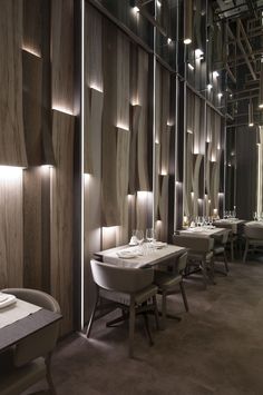 an empty restaurant with wooden walls and white tablecloths on the tables in front of them